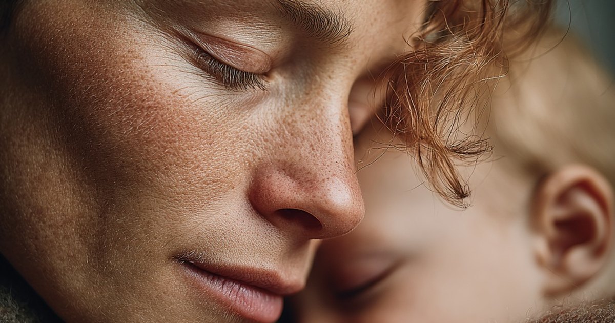 Jeune mère les yeux clos, joue posée contre la tête de son bébé endormi
