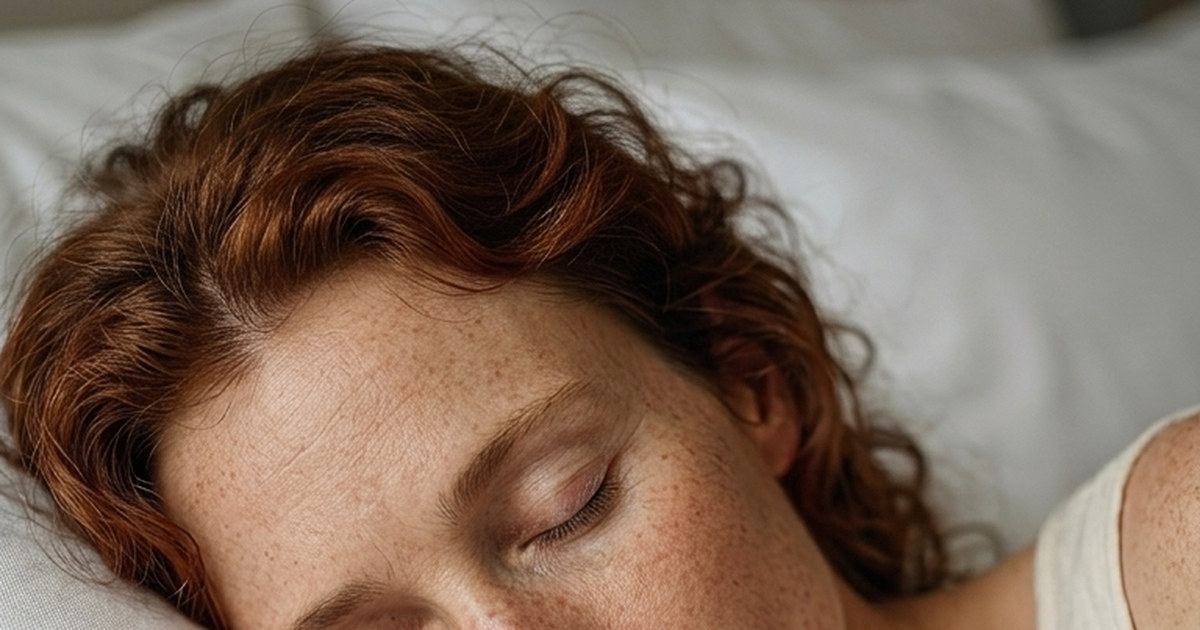Femme endormie sur un oreiller blanc, chevelure rousse bouclée, yeux fermés