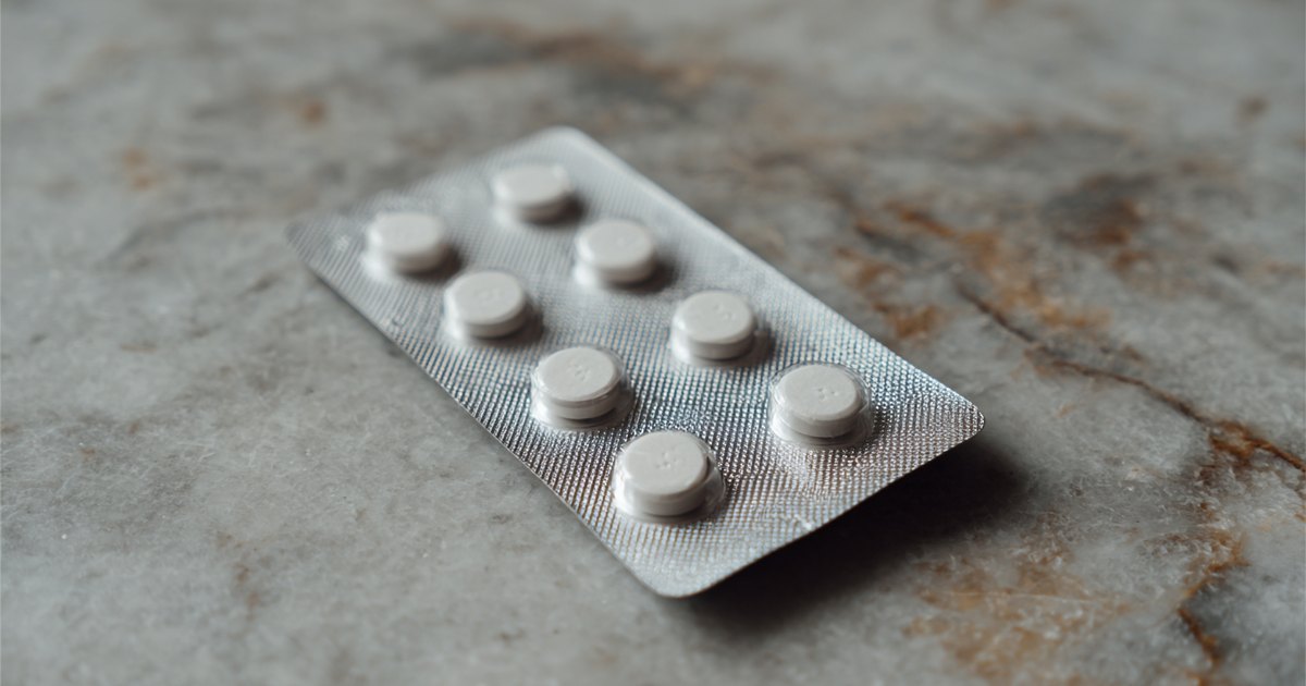 Plaquette de comprimés de minoxidil oral à faible dose posée sur une surface de marbre