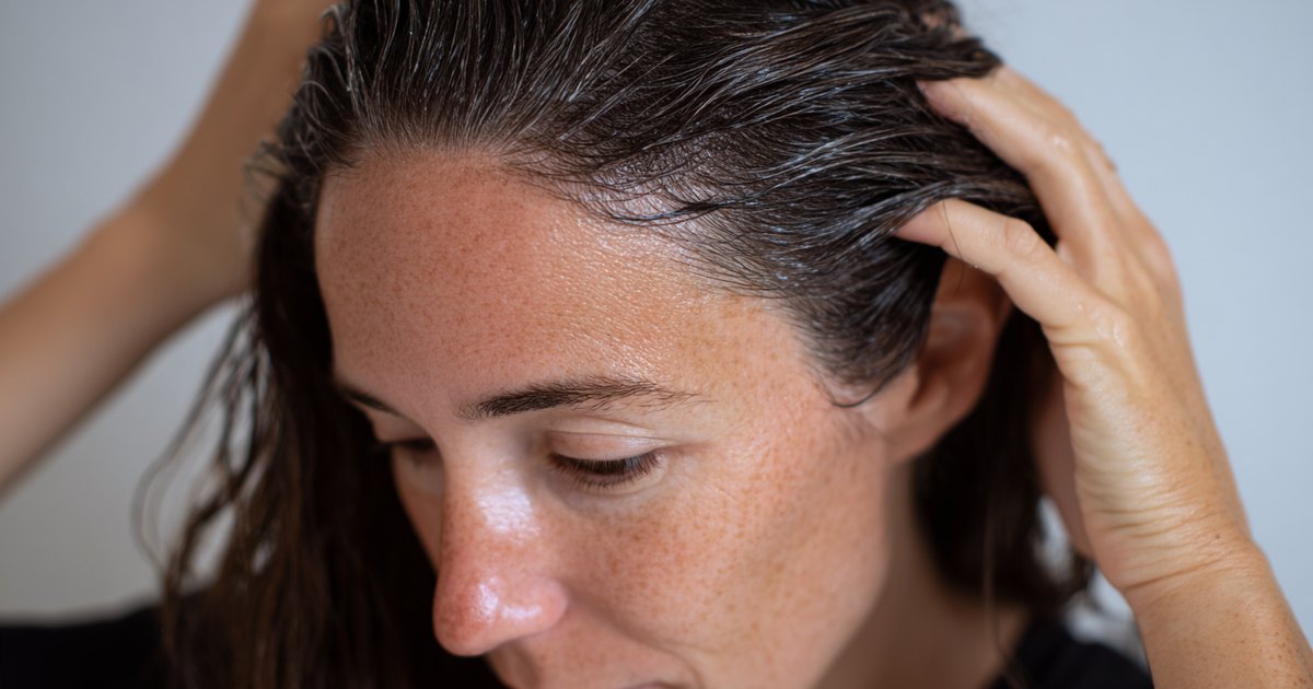 Femme appliquant une huile capillaire en massage sur le cuir chevelu et les racines