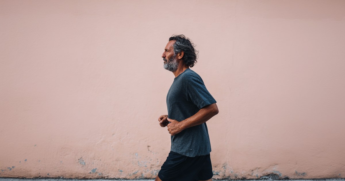 Un homme d'une cinquantaine d'années court le long d'un mur, chevelure fournie — le sport modéré est bénéfique pour le cuir chevelu